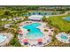 A lagoon style pool is surrounded by lounge chairs, umbrellas, and palm trees, with a clubhouse and lake in the background at 33716 Elm Hill Br, Wesley Chapel, FL 33545