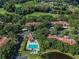 Aerial view showcases the community pool, pond, lush trees and building rooftops at 3476 Tarpon Woods Blvd, Palm Harbor, FL 34685