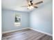 Bright bedroom features light blue walls, a ceiling fan, light wood-look flooring, and a large window at 3924 Kiah Dr, Wesley Chapel, FL 33543