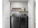Laundry room with washer and dryer behind opening white doors and wood shelving at 4121 W San Nicholas St, Tampa, FL 33629