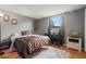Bedroom features a queen bed, wood floors, a window with natural light and gray walls at 4150 Pecos Dr, New Port Richey, FL 34653