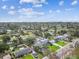 Neighborhood aerial view of the single story home with tree coverage under a bright blue, partly cloudy sky at 4461 Shore Acres Ne Blvd, St Petersburg, FL 33703