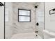 Bathroom featuring white tub with black fixtures and gray-marbled tiled wall at 4461 Shore Acres Ne Blvd, St Petersburg, FL 33703