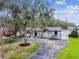 Charming single-story home featuring black trim, fresh landscaping, a carport, and a circular driveway at 4461 Shore Acres Ne Blvd, St Petersburg, FL 33703