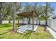 Backyard pergola with adjacent grass, white fence, and surrounding trees at 4461 Shore Acres Ne Blvd, St Petersburg, FL 33703