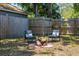 A seating area with stylish outdoor furniture centered around a rustic wood pile in a grass and leaf covered backyard at 4531 7Th N Ave, St Petersburg, FL 33713