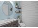 Powder room featuring a modern vanity, decorative shelves, and a stylish round mirror at 4770 Ballantrae Blvd, Land O Lakes, FL 34638