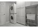 Well-organized laundry room with stacked washer and dryer, utility sink, and storage cabinets at 4770 Ballantrae Blvd, Land O Lakes, FL 34638