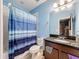Blue bathroom with shower, granite sink and vanity featuring a large mirror, and ample storage space at 4916 Rolling Green Dr, Wesley Chapel, FL 33543