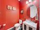 Stylish powder room with bright red walls, a modern glass bowl sink, and decorative accents at 4916 Rolling Green Dr, Wesley Chapel, FL 33543