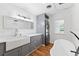 Bright bathroom featuring gray cabinets, a soaking tub, and a stackable washer/dryer at 509 Falmouth St, Temple Terrace, FL 33617