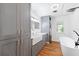 Modern bathroom featuring gray cabinets, a farmhouse sink, wood-look floors, and a soaking tub at 509 Falmouth St, Temple Terrace, FL 33617