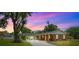 Charming single-story brick home with a long driveway, mature landscaping, and a covered front porch at twilight at 509 Falmouth St, Temple Terrace, FL 33617