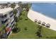 An aerial view of the condo building on the beach with green lawn, sand and beach umbrellas at 5701 Bahia Del Mar Cir # 108, St Petersburg, FL 33715