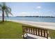 Scenic waterfront view with a sandy beach, bench, and palm tree on a sunny day at 5701 Bahia Del Mar Cir # 108, St Petersburg, FL 33715
