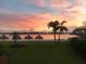 Sunset view of a waterfront featuring palm trees, tiki huts, and a bridge in the background at 5701 Bahia Del Mar Cir # 108, St Petersburg, FL 33715