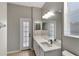 Bathroom featuring white vanity, large mirror, and a doorway to the backyard at 7732 Bulls Head Dr, Wesley Chapel, FL 33545