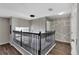 Second floor hallway with hardwood floors, view of foyer chandelier, and geometric wall trim at 7732 Bulls Head Dr, Wesley Chapel, FL 33545