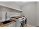 Laundry room with sink, countertop, and modern washer/dryer for efficient chore management at 7732 Bulls Head Dr, Wesley Chapel, FL 33545
