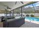 Screened patio with ample lounge seating provides a seamless indoor-outdoor living experience near the pool at 7818 Holiday Dr, Spring Hill, FL 34606
