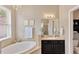 A bathroom features a bathtub, vanity, and chandelier at 7822 Atwood Dr, Wesley Chapel, FL 33545