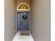 A welcoming front door featuring a decorative wreath and arched window above the gray-painted entrance at 7822 Atwood Dr, Wesley Chapel, FL 33545