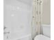 Bright bathroom with white tiled shower, bathtub, and floral curtain, complemented by a standard toilet at 9466 Forest Hills Cir, Tampa, FL 33612