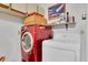 Well-lit laundry room featuring a stacked red washer and white dryer with storage and essential laundry supplies at 9466 Forest Hills Cir, Tampa, FL 33612