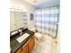Bathroom featuring a vanity with granite top and a shower-tub combo with stylish curtain at 9735 Riverchase Dr, New Port Richey, FL 34655