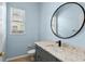 Bathroom featuring gray vanity with a round mirror and light-colored granite countertop at 10205 Deercliff Dr, Tampa, FL 33647