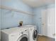 Functional laundry room features white appliances, wire shelving, and a neutral tile floor at 10205 Deercliff Dr, Tampa, FL 33647