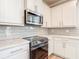 Updated kitchen with stainless steel appliances, white cabinets, and quartz countertops at 11291 Cay Spruce Way, San Antonio, FL 33576