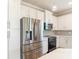 Bright kitchen features stainless steel appliances, white cabinets, and a subway tile backsplash at 11291 Cay Spruce Way, San Antonio, FL 33576