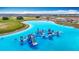 Stunning aerial view of a crystal-clear lagoon featuring an inflatable water park and watersport activities at 11291 Cay Spruce Way, San Antonio, FL 33576