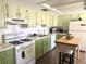 Functional kitchen with white appliances, green cabinetry, white tile and laminate countertops at 11807 Addison St, Spring Hill, FL 34609