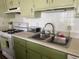 Efficient kitchen with a double sink, stove, and green cabinets, offering a practical cooking space at 11807 Addison St, Spring Hill, FL 34609