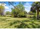 Lush backyard featuring well-manicured lawn, mature trees, and a stream in the distance at 12516 Cobble Stone Dr, Hudson, FL 34667
