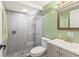 Updated bathroom with a glass-enclosed shower, modern fixtures, a gray vanity, and green accent wall at 12516 Cobble Stone Dr, Hudson, FL 34667