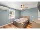 Cozy bedroom with blue walls, a ceiling fan, and a striped bed with a side table and wood flooring at 12516 Cobble Stone Dr, Hudson, FL 34667