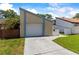 A tan house with blue trim, a white garage door, and a green lawn, bathed in the soft light of a partly cloudy day at 12516 Cobble Stone Dr, Hudson, FL 34667