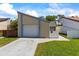 A charming tan home with blue trim, a white garage door, and a well-maintained lawn under a bright blue sky at 12516 Cobble Stone Dr, Hudson, FL 34667