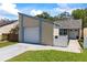 A cozy tan home with a white garage door, trimmed in blue, complemented by a quaint white fence and lush green lawn at 12516 Cobble Stone Dr, Hudson, FL 34667