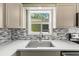 Close-up of kitchen sink and backsplash with a view out the window and quartz countertops at 12516 Cobble Stone Dr, Hudson, FL 34667