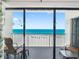 Condo balcony featuring chairs and a table with a view of the white sand beach and blue ocean at 13500 Gulf Blvd # 506, Madeira Beach, FL 33708