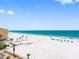 Beautiful view of a white sandy beach and the ocean, with buildings and palm trees at 13500 Gulf Blvd # 506, Madeira Beach, FL 33708