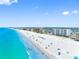 Wide aerial shot of a shoreline, featuring beachgoers, turquoise waters, and waterfront condo buildings at 13500 Gulf Blvd # 506, Madeira Beach, FL 33708