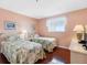 Cozy bedroom features two twin beds with floral quilts, wood floors, and natural light from a window at 13500 Gulf Blvd # 506, Madeira Beach, FL 33708