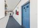 Inviting condo hallway leading to a vibrant blue entrance door with charming architectural details and safety features at 13500 Gulf Blvd # 506, Madeira Beach, FL 33708