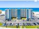 Exterior front view of a condo building with large parking area, landscaping, and distant beach views at 13500 Gulf Blvd # 506, Madeira Beach, FL 33708