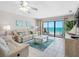 Living room with tile floors, ceiling fan, sliding doors to balcony, and beautiful ocean view at 13500 Gulf Blvd # 506, Madeira Beach, FL 33708
